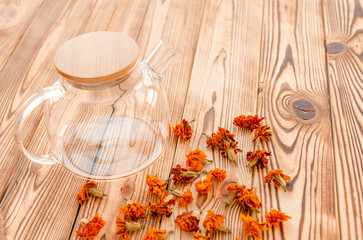 Medicinal plants. Dried marigold flowers and a teapot for brewing on the table