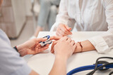 Fototapeta Panele - Unrecognizable female nurse healthcare checking blood sugar level of senior patient