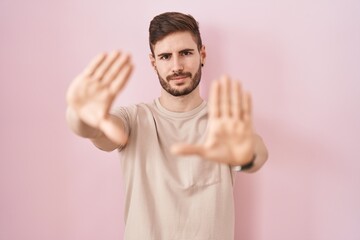 Poster - Hispanic man with beard standing over pink background doing frame using hands palms and fingers, camera perspective