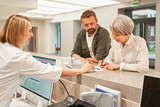 Fototapeta Panele - Patients signing agreement and talking to professional receptionist in clinic