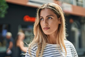 Canvas Print - Young blonde woman looking to the side with serious expression at street