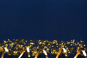 Canvas Print - Confetti stars and gold streamer on dark blue background, flat lay. Christmas celebration card, blank mockup.