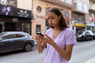 Sticker - Young african american woman using smartphone with worried expression at street