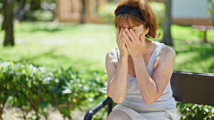 Wall Mural - Middle age woman sitting on bench stressed at park