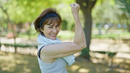 Wall Mural - Middle age woman wearing sportswear doing strong gesture with arm at park