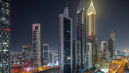 Wall Mural - Panorama showing aerial view of Dubai International Financial District with many skyscrapers night timelapse.