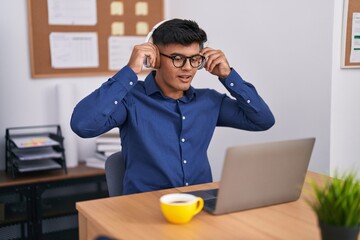 Poster - Young hispanic man business worker using laptop and headphones working at office