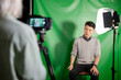 © PhotoAlto - Young adult man giving an interview while sitting against green screen