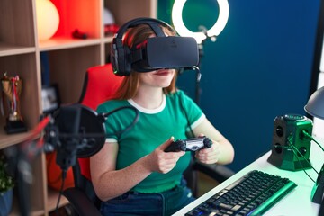 Poster - Young redhead woman streamer playing video game using virtual reality glasses and joystick at gaming room