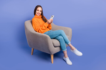 Poster - Full length size photo of cheerful influencer blogger lady browsing cellphone sitting armchair isolated on violet color background