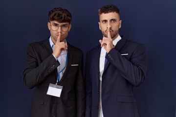 Poster - Two hispanic business men wearing business clothes asking to be quiet with finger on lips. silence and secret concept.