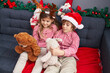 © Krakenimages.com - Brother and sister playing with teddy bears sitting on sofa by christmas decoration at home