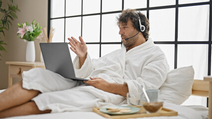 Canvas Print - Young hispanic man wearing bathrobe having video call at bedroom