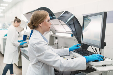 team of laboratory technicians conduct series of tests on  chemical analyzer in laboratory. Two female scientists work in modern equipped computer laboratory doing tests with tubes and pipette