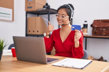 Wall Mural - Asian young woman working using computer laptop and credit card smiling happy and positive, thumb up doing excellent and approval sign