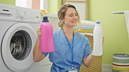 Poster - Young blonde woman professional cleaner holding detergent bottles at laundry room