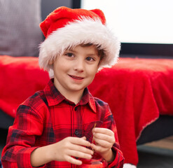 Adorable hispanic boy smiling confident holding decorating christmas ball at home