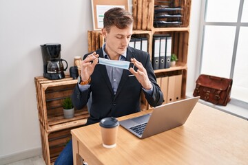 Young man business worker holding medical mask working at office