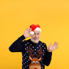 Sticker - Senior man in Christmas sweater and Santa hat on orange background