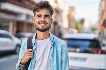 Wall Mural - Young hispanic man student smiling confident wearing backpack at street