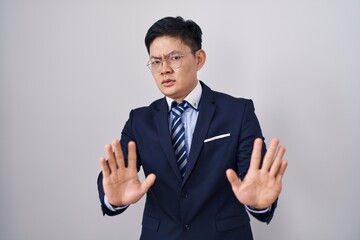 Sticker - Young asian man wearing business suit and tie moving away hands palms showing refusal and denial with afraid and disgusting expression. stop and forbidden.