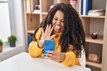 Wall Mural - Plus size hispanic woman using smartphone sitting on the table looking positive and happy standing and smiling with a confident smile showing teeth