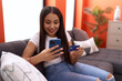 © Krakenimages.com - Young arab woman using smartphone and credit card sitting on sofa at home