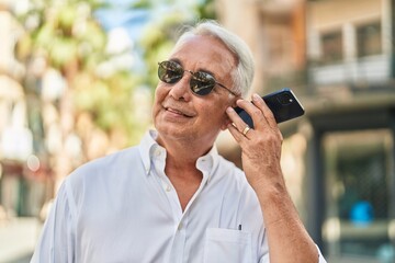 Wall Mural - Middle age grey-haired man smiling confident listening audio message by the smartphone at street