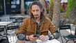 © Krakenimages.com - Young hispanic man tourist using smartphone sitting on table at coffee shop terrace