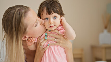 Wall Mural - Mother and daughter sitting on bed kissing at bedroom