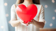 a young woman holds a heart-shaped balloon