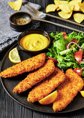 Poster - breaded fish fillet with salad on black plate