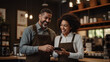 © Studio Nova - Cafe worker and manager smiling and engaging with each other while using a tablet