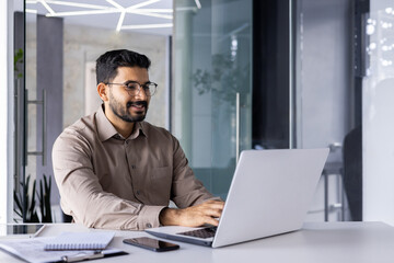 Businessman happy successful and smiling working with laptop inside office at workplace, man satisfied with financial result prepares report, accountant financier typing on computer keyboard.