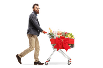 Poster - Full length shot of a bearded guy walking and pushing a shopping cart with food tied with a red ribbon