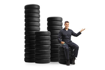 Sticker - Auto mechanic sitting on a pile of tires and gesturing welcome