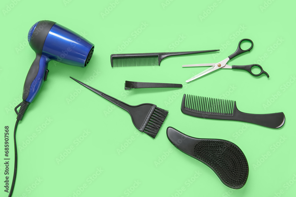 Different hairdressing tools on green background