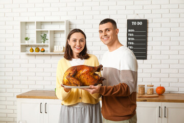 Poster - Young couple with turkey in kitchen on Thanksgiving Day