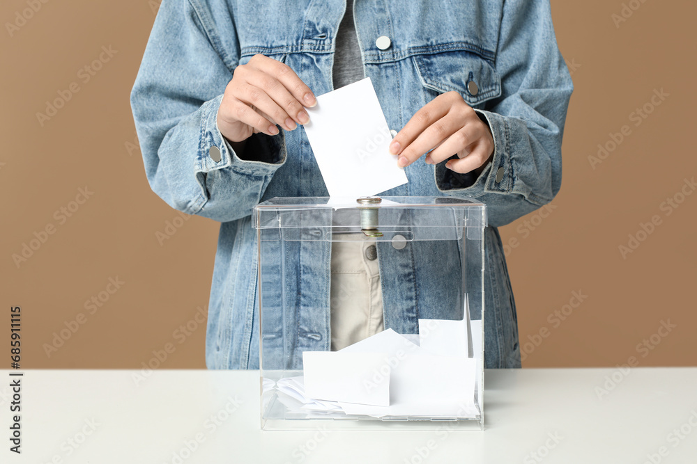 Voting woman near ballot box on beige background