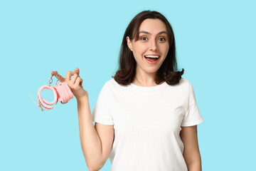 Poster - Beautiful young woman with handcuffs on blue background