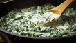 Pan with creamed spinach which is stirred with a wooden mixing spoon.