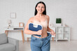 Beautiful young happy woman in loose jeans with scales at home. Weight loss concept