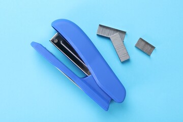 Wall Mural - Stapler with staples on light blue background, flat lay