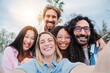 © Jose Calsina - Group of joyful best friends having fun and laughing taking a selfie portrait together. Friendly young adult people smiling and looking at camera outside. Multiracial buddies on a social gathering