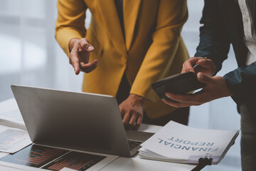 Two Asian businessmen discuss the working information of a financial investment project. Marketing and growth strategies and company revenue calculations Save data to a laptop computer in the office.