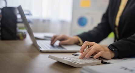 Sticker - Businesswoman accountant using calculator and laptop for financial data saving in office room, Business financial, tax, accounting concept