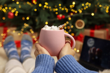 Wall Mural - Woman drinking delicious cocoa and watching Christmas movie at home, closeup