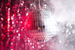 The disco ball is illuminated with red light