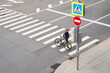 © nuclear_lily - Man crosses the road at a pedestrian crossing and carries a bicycle next to him. View from above.