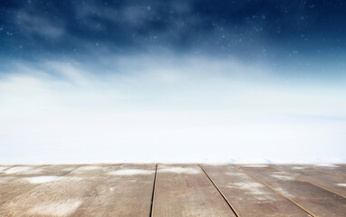 Poster - Wooden floor against blue sky with white clouds and snowflakes at the night blue sky background. High quality photo